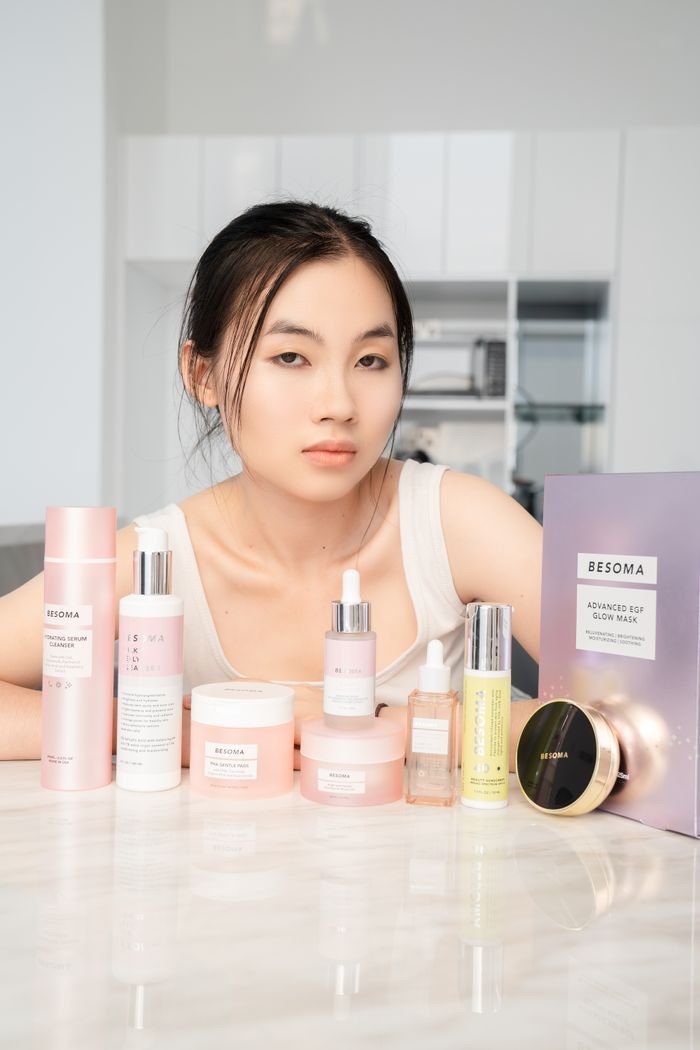 The Art of Drawing Readers In: Your attractive post title goes here Portrait of an Asian woman with a variety of Besoma skincare products on a table.