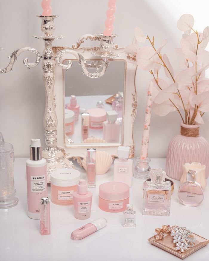services-01 Charming arrangement of pink cosmetics with candles and a mirror, exuding elegance.