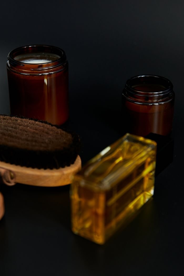 about-us-02 Stylish spa essentials including amber bottles and grooming brush on a dark surface.